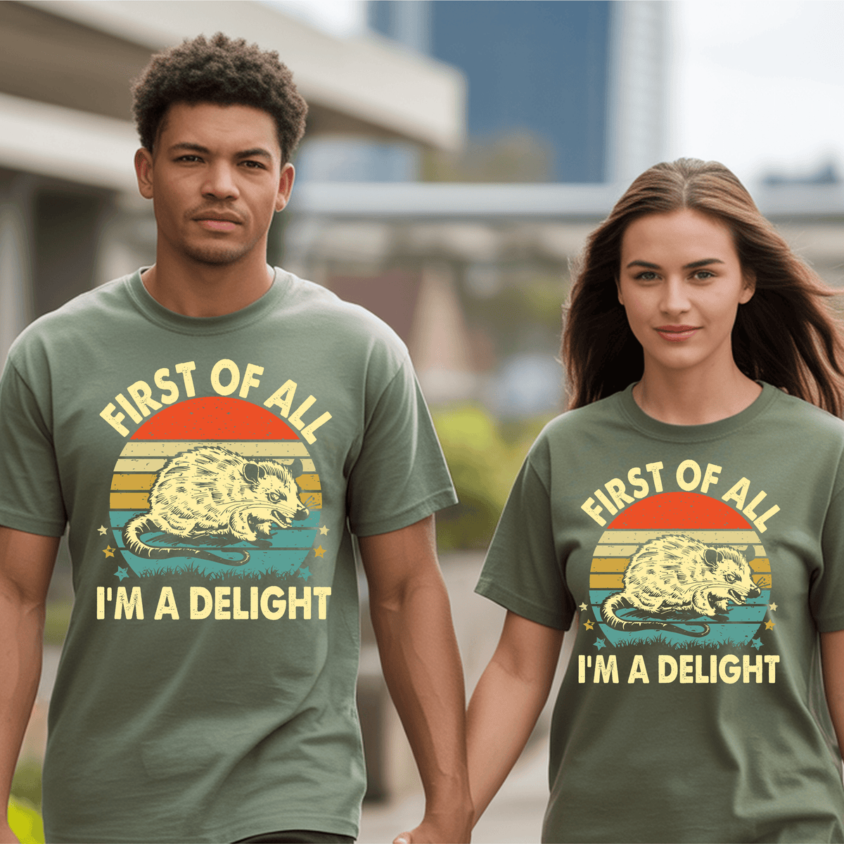 Couple wearing matching First of All I’m a Delight graphic t-shirts against a city backdrop.