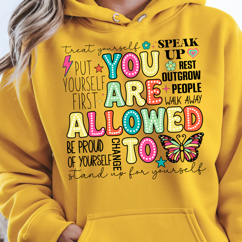 You Are Allowed To Hoodie inspirational affirmation hoodie with colorful lettering and cheerful icons on a yellow background.