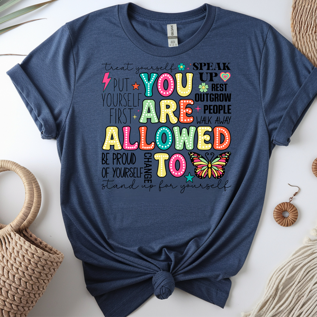 you are allowed to graphic t-shirt featuring colorful affirmations and a butterfly design on a navy blue background.