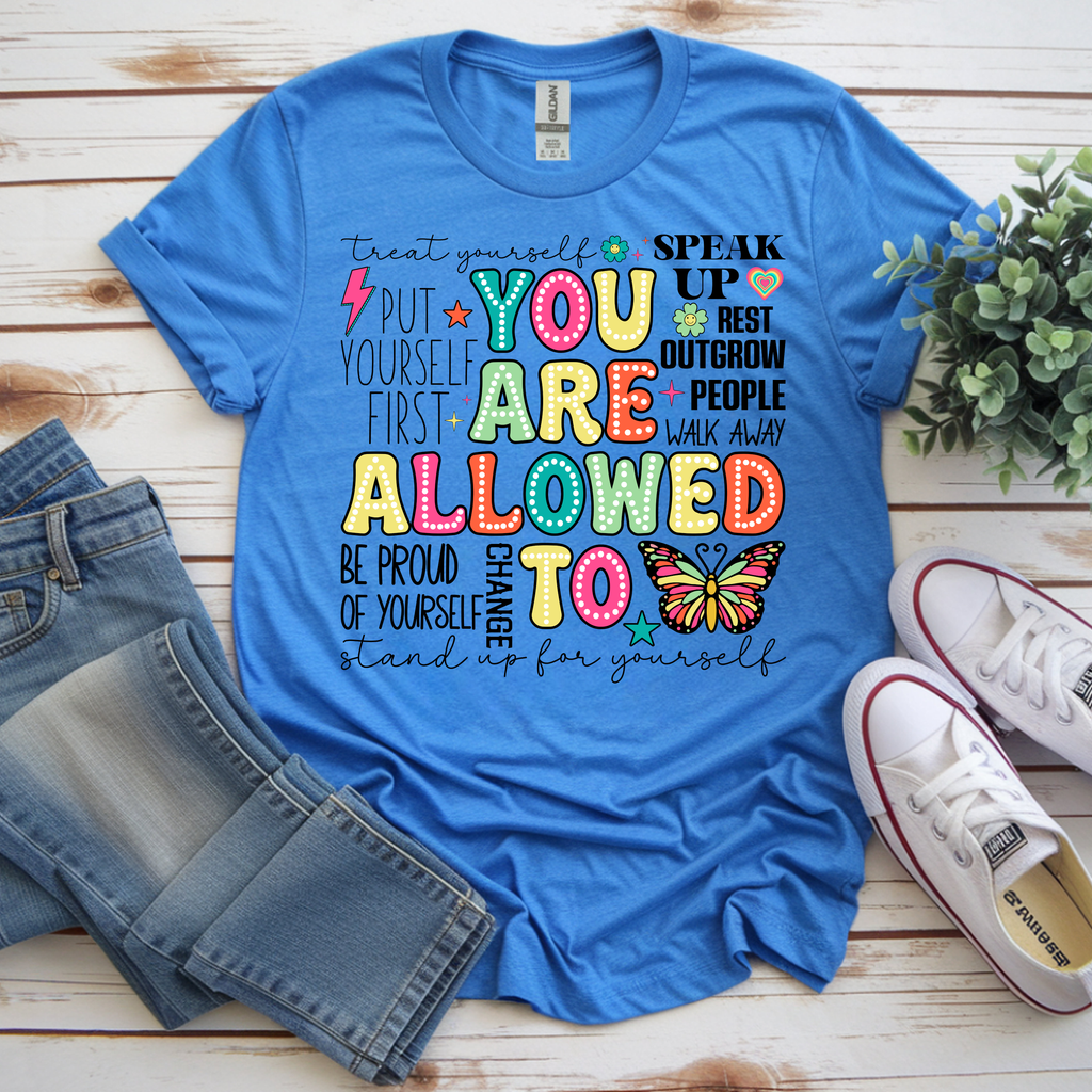 You Are Allowed To graphic t-shirt in blue with positive affirmations and colorful design, paired with denim shorts and sneakers.